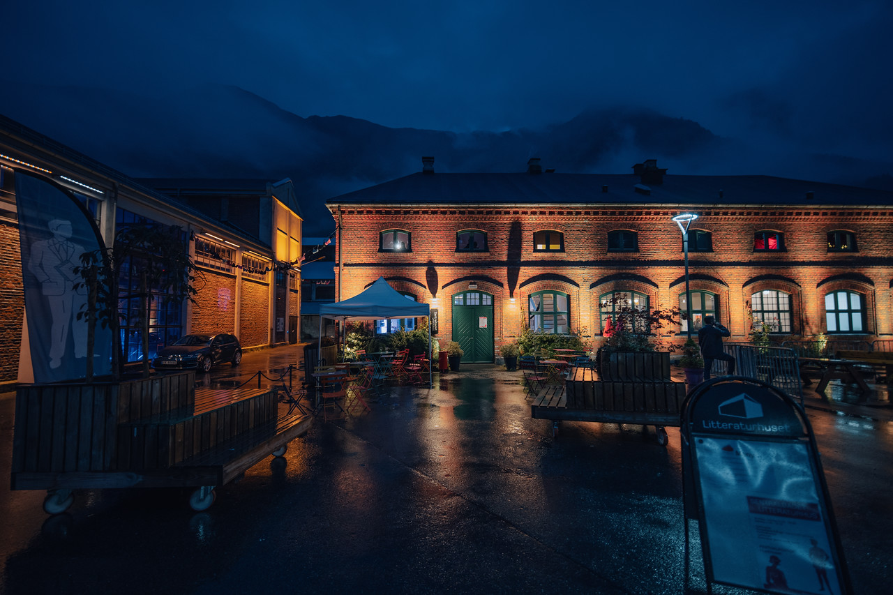 Sentralbadet litteraturhus opplyst av lyskastere en mørk høstkveld. Foto.
