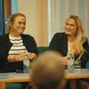 Halvnært bilde av forfattere Olaug Nilsen og Marit Eikemo som sitter i en sofa på scenen på Odda bibliotek. Publikum skimtes i bildets nedre kant. Foto.